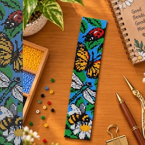 May include: A rectangular beaded bookmark featuring a vibrant nature-themed pattern with a red ladybug, an orange monarch butterfly, a blue dragonfly, and a yellow and black bumblebee resting on a white daisy against a bright blue background.