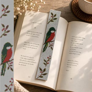 Puede incluir: Un marcapáginas de cuentas con un diseño de un pájaro rojo y verde en una rama con bayas. El marcapáginas está en un libro abierto con el título "A Quiet Place".