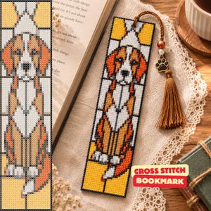 May include: A rectangular cross-stitch bookmark featuring a stained-glass style design of a beagle dog in shades of orange, white, and black. The bookmark is finished with a brown cord, a small metal paw print charm, and a brown fabric tassel.