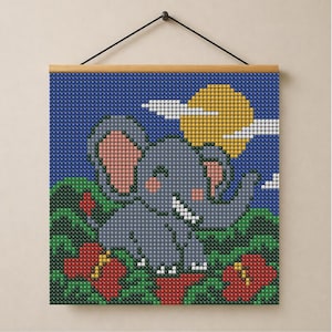 Op de afbeelding: Een vierkante diamond painting wandhanger met een grijze olifant met roze oren en wangen, geplaatst tussen groen gebladerte en rode bloemen tegen een donkerblauwe lucht met een gele zon en witte wolken, opgehangen aan een houten frame.