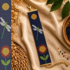 May include: A rectangular beaded bracelet featuring a dark blue background with a yellow sun, a white dragonfly with a green body, and a red and yellow flower with a green stem. The bracelet has gold-toned metal end caps and a gold chain clasp.