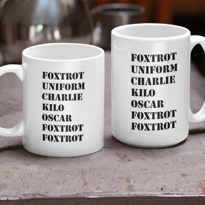 May include: Two white ceramic mugs with black text. The text on both mugs reads "FOXTROT UNIFORM CHARLIE KILO OSCAR FOXTROT FOXTROT".