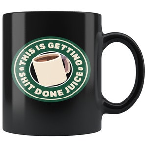 May include: Black ceramic coffee mug with a white and green sticker. The sticker features a coffee cup graphic and the text "THIS IS GETTING SHIT DONE JUICE". The mug has a curved handle.