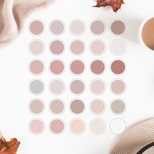 Könnte beinhalten: Eine Sammlung runder Aufkleber in verschiedenen Rosa-, Beige- und Grautönen, angeordnet in einem Rastermuster. Eine Tasse Kaffee, eine Strickdecke, ein Strohhut und ein dekorativer Ball sind ebenfalls zu sehen.