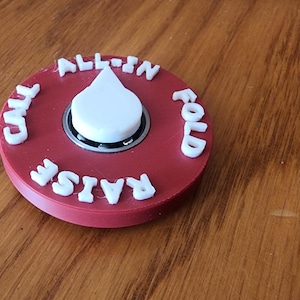 May include: Red plastic spinner with white lettering. The spinner has the words "Call", "Raise", "All-in", and "Fold" around the edge. The spinner is designed to be used for playing poker.