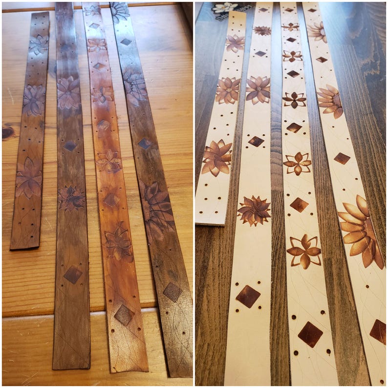 May include: Four leather strips with a floral design, two are stained brown and two are natural leather. The strips are lined up on a wooden surface.