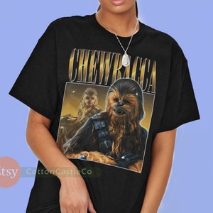 May include: Black t-shirt with a vintage-style graphic of Chewbacca from Star Wars. The graphic features Chewbacca with the text "CHEWBACCA" above him.