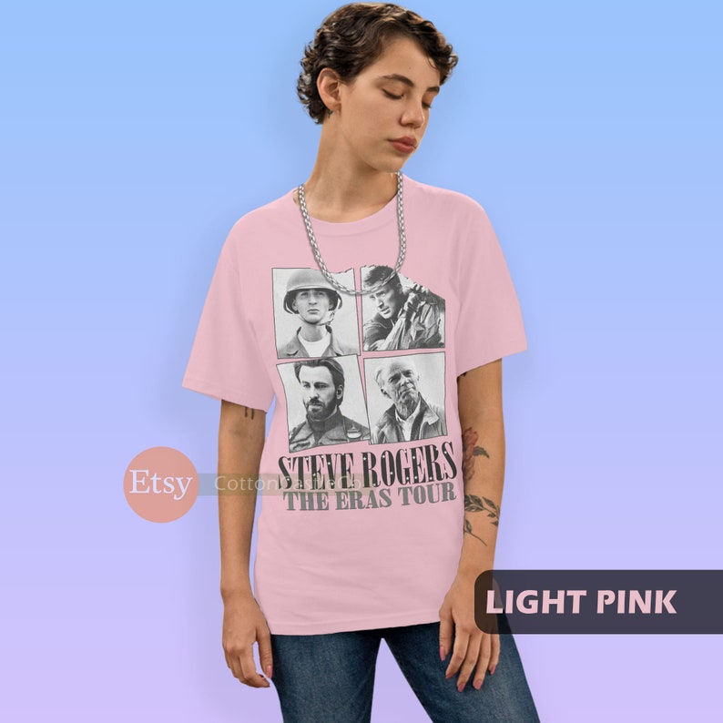 May include: Light pink t-shirt with a black and white image of four different versions of Steve Rogers from the Marvel Cinematic Universe. The text "STEVE ROGERS THE ERAS TOUR" is printed on the shirt.