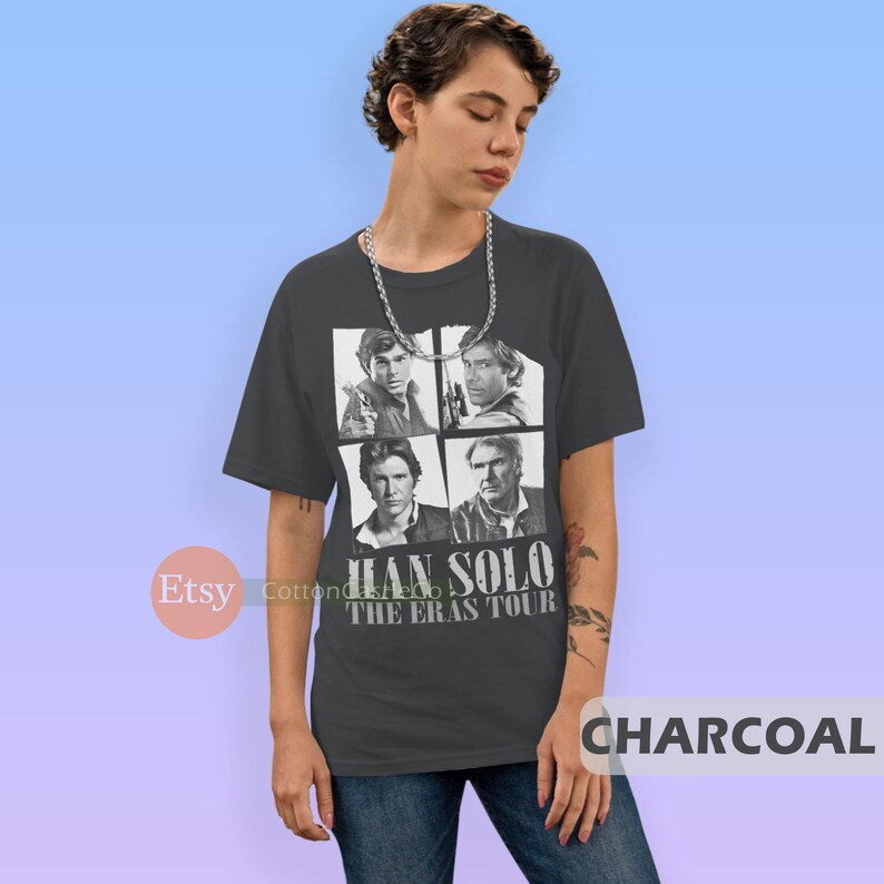 May include: A charcoal gray t-shirt featuring a collage of four black and white images of Han Solo from different Star Wars movies. The text "HAN SOLO THE ERAS TOUR" is printed in white on the shirt.
