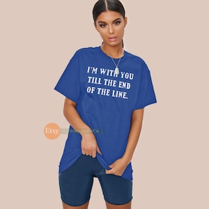 May include: Royal blue t-shirt with the text "I'M WITH YOU TILL THE END OF THE LINE" in white. The shirt is a loose fit and has short sleeves. The model is also wearing dark blue shorts.
