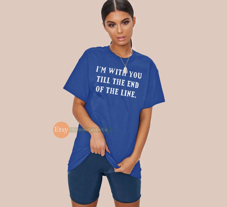 May include: Royal blue t-shirt with the text "I'M WITH YOU TILL THE END OF THE LINE" in white. The shirt is a loose fit and has short sleeves. The model is also wearing dark blue shorts.
