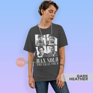 May include: Dark heather grey t-shirt featuring a collage of four images of Han Solo from different Star Wars movies. The text "Han Solo The Eras Tour" is printed below the images.