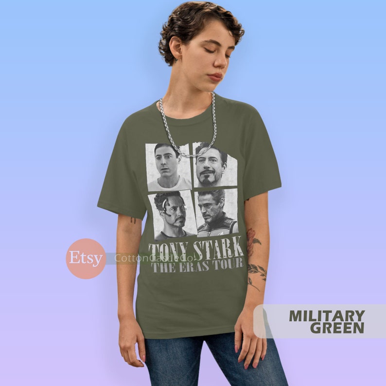 以下が含まれることがあります： アイアンマン映画のトニー・スタークの白黒写真4枚をコラージュした緑色のTシャツ。Tシャツには「TONY STARK THE ERAS TOUR」の文字がプリントされています。