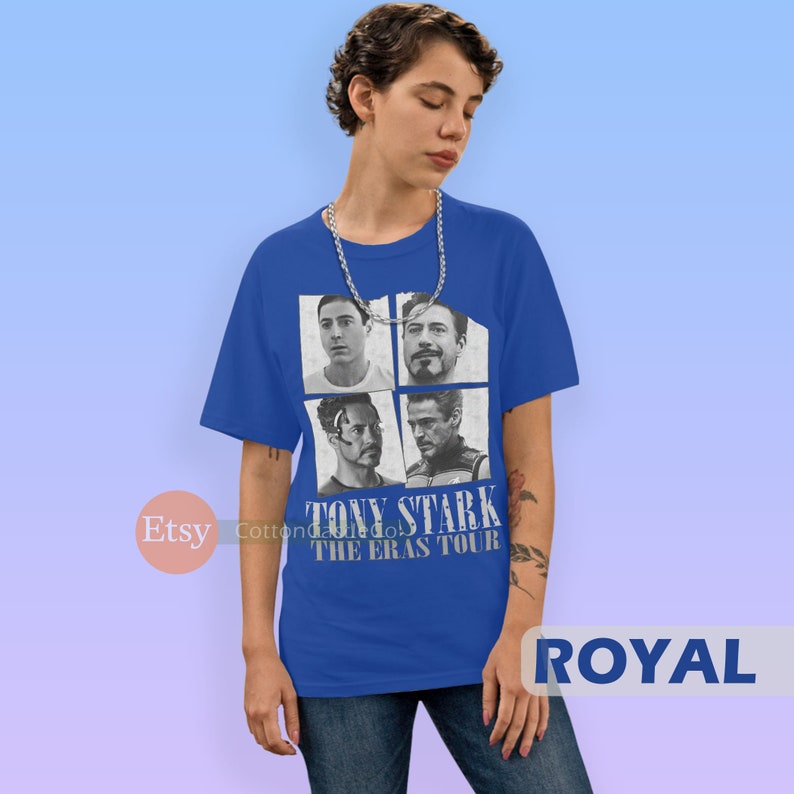 以下が含まれることがあります： アイアンマン映画のトニー・スタークの画像4枚がプリントされたロイヤルブルーのTシャツ。Tシャツには「トニー・スターク・ザ・エラス・ツアー」の文字がプリントされています。