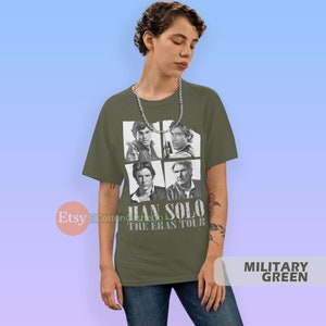 May include: A green t-shirt with a black and white image of Han Solo from Star Wars. The shirt has the text "Han Solo The Eras Tour" printed on it.