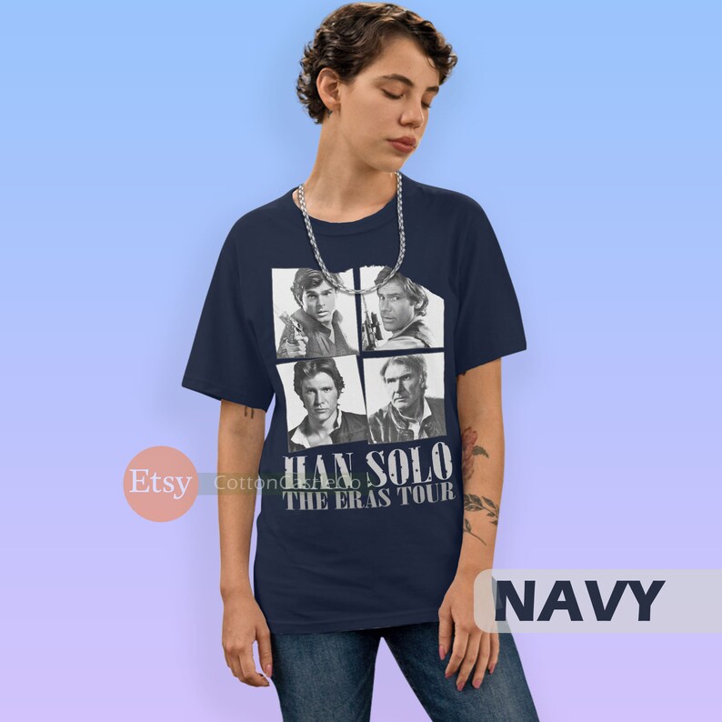 May include: A navy blue t-shirt with a graphic of four images of Han Solo from different Star Wars movies. The text "HAN SOLO THE ERAS TOUR" is printed on the shirt.