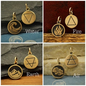 Puede incluir: Cuatro amuletos de metal de color dorado con diferentes símbolos que representan los cuatro elementos: agua, fuego, tierra y aire. Cada amuleto es un círculo con un símbolo en relieve en su interior. Los símbolos son una ola, una llama, una montaña y una nube.