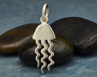 May include: A silver charm in the shape of a jellyfish. The charm has a rounded top and flowing tentacles.