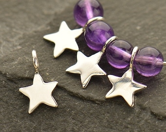 May include: Five silver star charms hang from a strand of purple amethyst beads. The charms are smooth and have a slightly rounded shape.