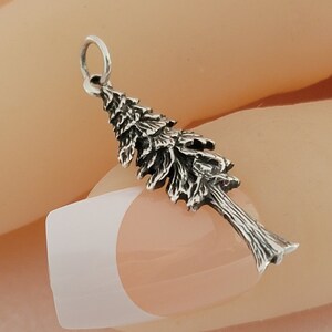 May include: A silver charm in the shape of a pine tree. The charm is detailed with branches and needles.