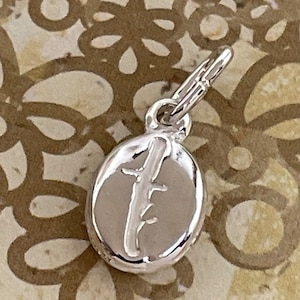 May include: Silver charm in the shape of an oval with the number "4" engraved on it. The charm has a loop at the top for attaching to a bracelet or necklace.