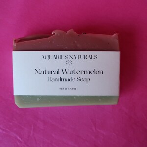 May include: A green and pink bar of handmade soap with a white label that reads "Aquarius Naturals" and "Natural Watermelon Handmade Soap" with a net weight of 4.5 oz.