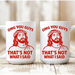 Pu&ograve; includere: Due tazze di ceramica bianca con una grafica rossa di una persona con una corona di spine. Le tazze hanno il testo "OMG YOU GUYS" e "THAT'S NOT WHAT I SAID" in rosso. Le tazze sono su una superficie di legno.