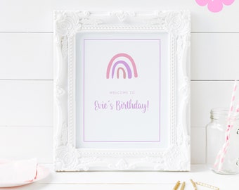 May include: A white frame with a printable sign that says "Welcome to Evie's Birthday!" with a rainbow graphic in pink, purple, and orange.