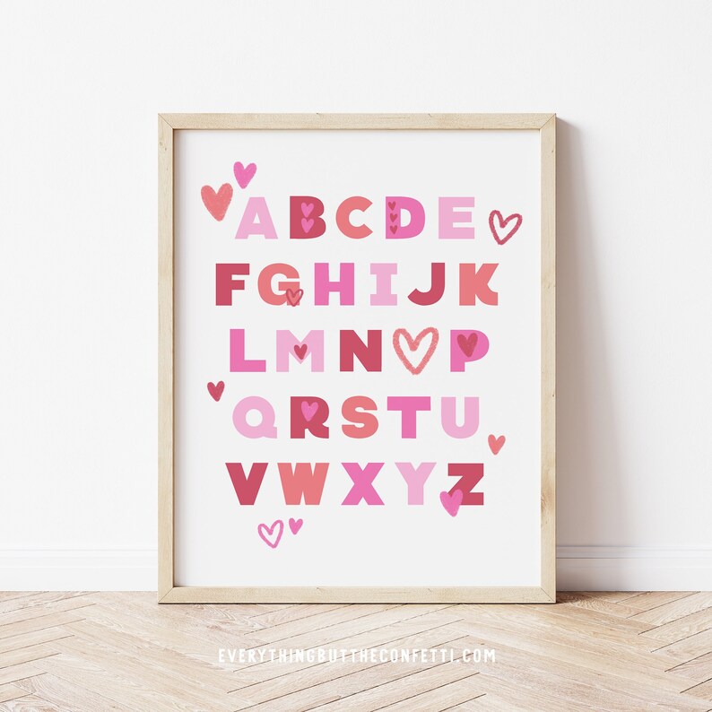 Peut inclure: Un tableau d'alphabet imprimable avec des lettres et des c&oelig;urs roses et rouges. Les lettres sont en gras, en caract&egrave;res gras. Le tableau est encadr&eacute; dans un cadre en bois clair.