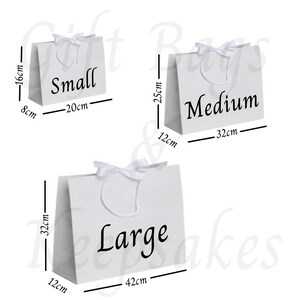 Pode incluir: Tr&ecirc;s sacolas de presente brancas rotuladas como "Small", "Medium" e "Large". A sacola pequena tem 8cm x 20cm x 16cm, a m&eacute;dia tem 12cm x 32cm x 25cm e a grande tem 12cm x 42cm x 32cm. Cada sacola tem uma al&ccedil;a de fita branca.
