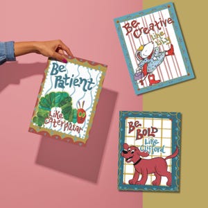 Op de afbeelding: Drie kleurrijke kaarten met inspirerende boodschappen en illustraties uit populaire kinderboeken. De eerste kaart zegt "Wees geduldig zoals de rups" en toont een groene rups. De tweede kaart zegt "Wees creatief zoals Emily" en toont een witte muis. De derde kaart zegt "Wees dapper zoals Clifford" en toont een rode hond.