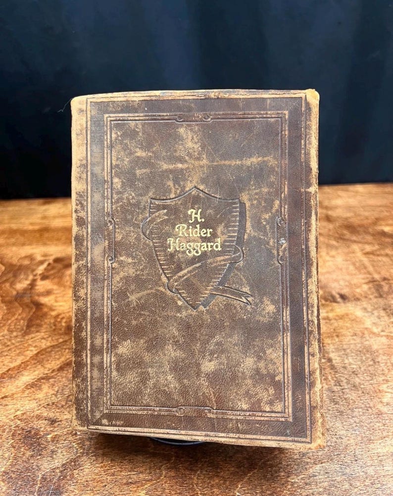 以下が含まれることがあります： 茶色の革装丁のヴィンテージ本で、表紙に「H. Rider Haggard」のタイトルがエンボス加工されています。 本には、著者の名前が装飾的なフォントで書かれた盾のデザインがあります。 表紙には使用感があり、クラシックでアンティークな外観になっています。