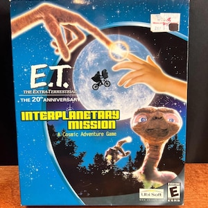 May include: A blue box for the video game "E.T. The Extra-Terrestrial: Interplanetary Mission". The box art features E.T., a moon, and hands reaching out. The game is rated "Everyone" by the ESRB.