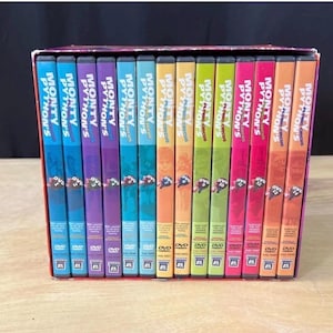 Könnte beinhalten: Eine Sammlung von vierzehn Monty Python's Flying Circus DVD-Hüllen, die in einer Reihe angeordnet sind. Die Buchrücken sind farblich in Blau, Lila, Gelb, Grün, Pink und Orange gestaltet und mit Serientitel, Bandnummer und DVD-Logo versehen.