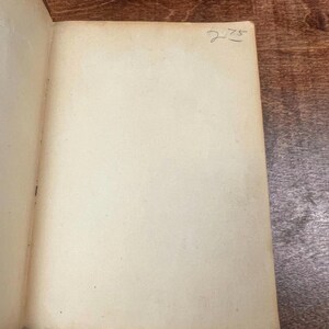 以下が含まれることがあります： 開いた本で、古びたオフホワイトのページがあります。右ページの右上隅には、手書きの数字「275」があります。本のページはわずかに黄色くなっており、古さを感じさせます。本は木製の表面に開かれています。