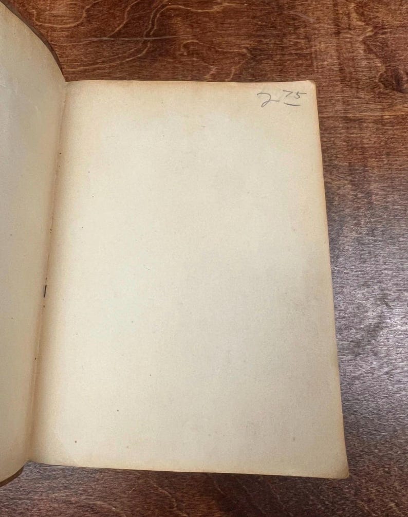 以下が含まれることがあります： 開いた本で、古びたオフホワイトのページがあります。右ページの右上隅には、手書きの数字「275」があります。本のページはわずかに黄色くなっており、古さを感じさせます。本は木製の表面に開かれています。