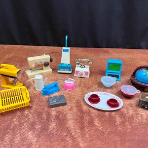 Könnte beinhalten: Eine Sammlung von Miniaturspielzeugen, darunter ein gelber Mixer, eine Nähmaschine, ein Staubsauger, ein Telefon, ein Laptop und ein Globus. Weitere Artikel sind ein Teeservice, ein Bügeleisen und eine Kaffeemühle. Die Spielzeuge sind aus Kunststoff und in verschiedenen Farben.
