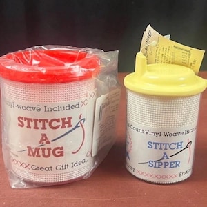 K&ouml;nnte beinhalten: Zwei Bastelsets zur Gestaltung von Trinkgef&auml;&szlig;en. Das linke Set ist ein Stitch A Mug mit rotem Deckel in Klarsichtfolie. Das rechte Set ist ein Stitch A Sipper mit gelbem Deckel und Trinkhalm&ouml;ffnung, mit wei&szlig;em Vinyl-Gewebe f&uuml;r Handarbeiten.