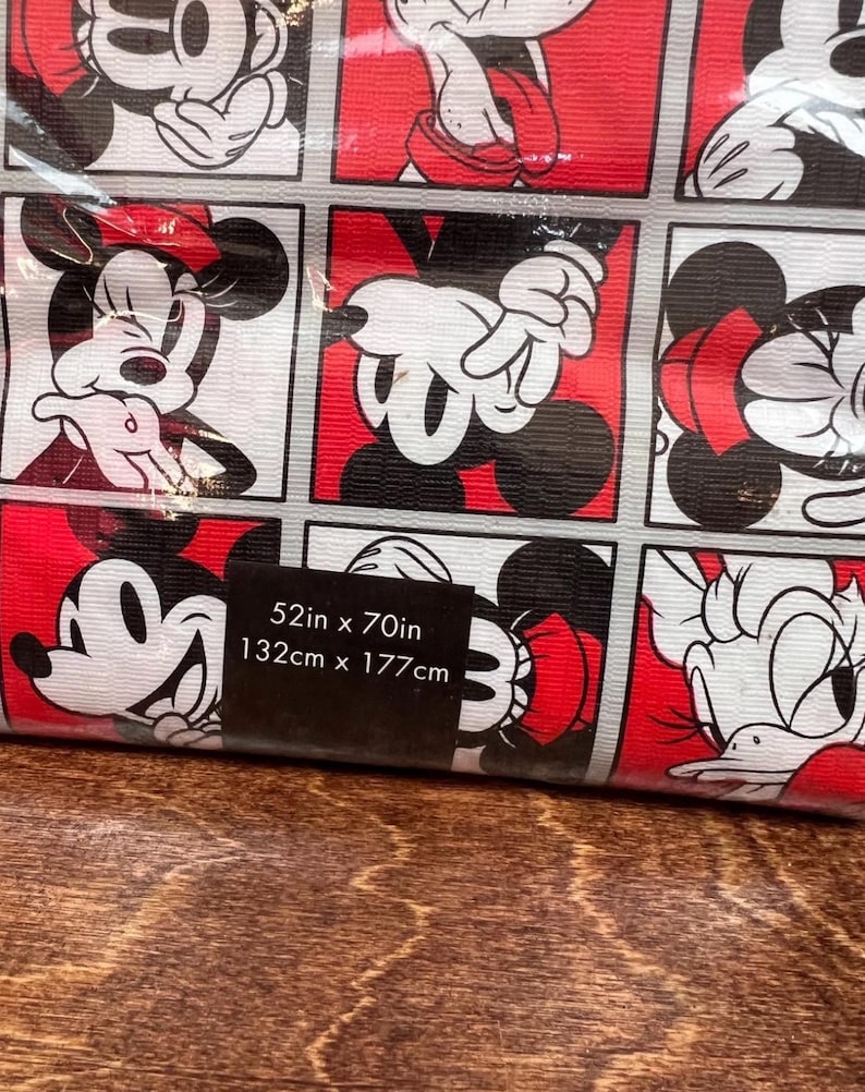 以下が含まれることがあります： ミッキーマウスとミニーマウスの白、黒、赤の正方形の繰り返し模様が特徴の、丸められた布地。サイズは132cm x 177cmです。布地は木製の表面にあります。