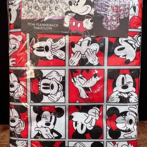以下が含まれることがあります： 赤、黒、白のミッキーマウスのテーブルクロス。テーブルクロスのサイズは132cm x 177cmです。デザインは、赤と黒の正方形の中に様々なポーズのミッキーマウスが描かれています。パッケージには「Disney Mickey Mouse」と「PEVA Flannelback Tablecloth」の文字が含まれています。