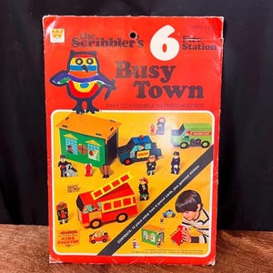 May include: A vintage "Busy Town" playset box with a red background. The box features illustrations of a fire station, fire truck, and other vehicles. The text "Easy to Assemble for Preschoolers" is visible.