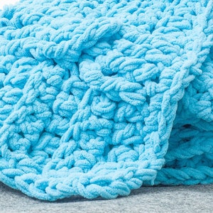 May include: A soft, blue knitted throw blanket with a chunky knit texture.