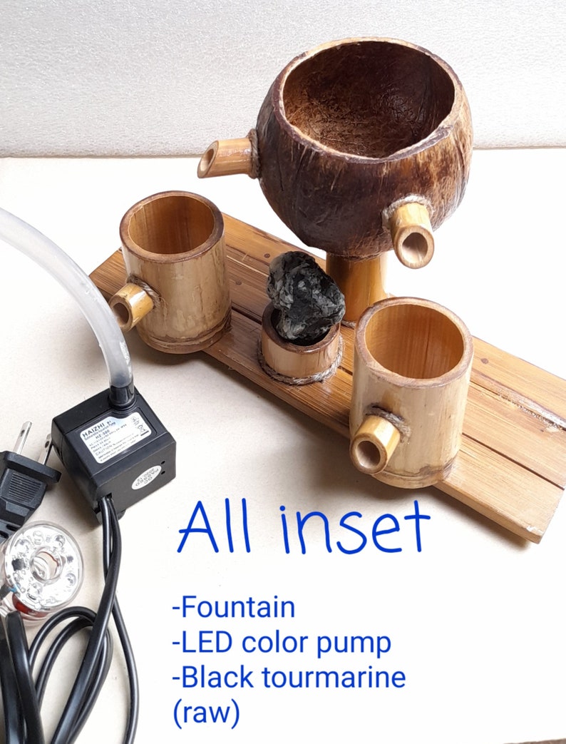 May include: A tabletop fountain made of bamboo and coconut with a black tourmaline stone. The fountain includes a small LED color pump and a clear plastic tube.