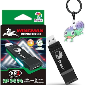 May include: A black Brook Wingman XB2 USB controller converter with a white chameleon logo and text, packaged in a green and black box featuring the text Wingman Converter, and a matching chameleon keychain with a black metal ring.