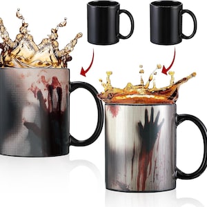 May include: A black heat-sensitive mug with a black handle. When hot liquid is added, a spooky handprint and blood-like stains appear. Two additional black mugs are shown.
