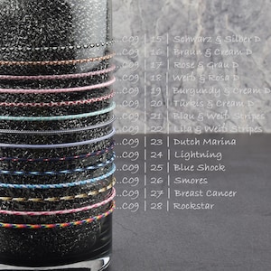 May include: A close-up of a glass jar filled with different colored cords. Each cord is labeled with a number and a color combination. The cords are arranged vertically in the jar, with the top of the jar visible at the top of the image. The cords are all about 1/4 inch in diameter. The cords are made of a variety of materials, including cotton, nylon, and polyester.