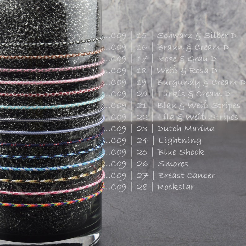 May include: A close-up of a glass jar filled with different colored cords. Each cord is labeled with a number and a color combination. The cords are arranged vertically in the jar, with the top of the jar visible at the top of the image. The cords are all about 1/4 inch in diameter. The cords are made of a variety of materials, including cotton, nylon, and polyester.