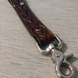 May include: A brown leather key chain with a braided design and a silver swivel clasp.
