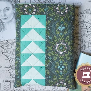May include: A green fabric book cover with a white and teal geometric pattern on the front. The cover has a floral design on the back. The text "Sewing Pattern" is on a brown circle with a sewing machine icon.