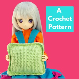 Puede incluir: Una muñeca sostiene una almohada de crochet verde. El texto "A Crochet Pattern" está en un cuadro azul.